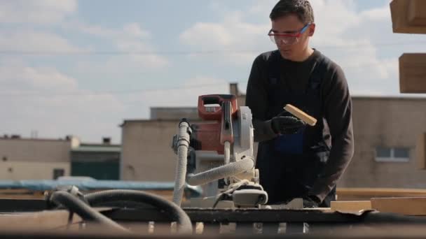 Trabajador industrial joven carpintero utilizando la máquina de corte de madera. hombre corta tablones de madera . — Vídeos de Stock