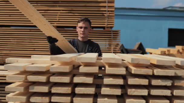 El hombre pliega tablones de madera. Montones de tablones cuadrados de madera para muebles . — Vídeos de Stock