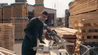 Yetişkin marangoz işçisi ahşap kesme makinesi kullanarak inşaat gözlükleri giyiyor. adam ahşap plakalar keser.