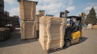 Ambardaki ahşap paletleri işleyen forklift operatörü. Adam yükleyici Dor kullanarak ahşap plakalar paketi.