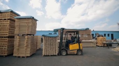 Ambardaki ahşap paletleri işleyen forklift operatörü. Adam yükleyici Dor kullanarak ahşap plakalar paketi.