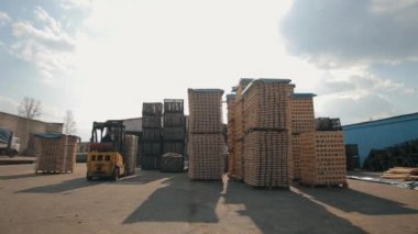 Ambardaki ahşap paletleri işleyen forklift operatörü. Adam yükleyici Dor kullanarak ahşap plakalar paketi.