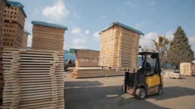 Ambardaki ahşap paletleri işleyen forklift operatörü. Adam yükleyici Dor kullanarak ahşap plakalar paketi.