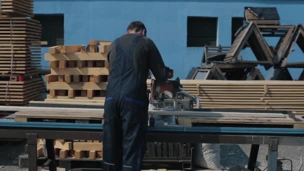 Achteraanzicht van industriële jonge timmerman werknemer in speciale uniform met behulp van hout snijmachine. — Stockvideo