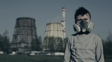 Genç bir maske. Endüstriyel sigara borusu karşı gaz maskesi solunum çocuk çekim çekildi. Hava kirliliği konsepti. Adam tatmin olmuyor.