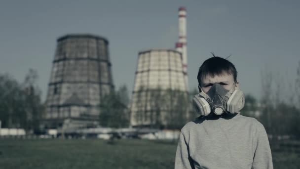 Close up retrato de menino vestindo poluição máscara contra chaminés de fábrica. Conceito de poluição atmosférica. O cara se vira e olha para a planta — Vídeo de Stock