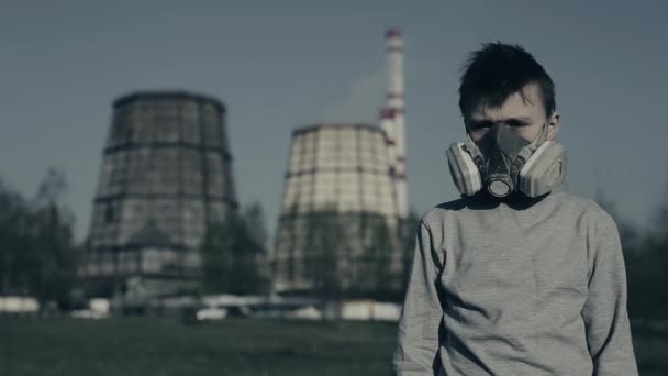 Teenager in mounth mask. Boy in gas mask respirator against the industrial smoking pipe taken closeup. Air pollution concept. Guy is dissatisfied shakes around — Stock Video