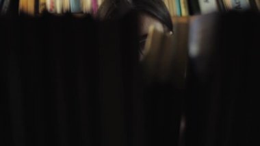 çekici bir genç kadın bir kitaplık kitaplığı için bir kitap arıyorum