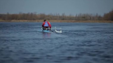 Bir kano nehir üzerinde kürek Atlet arka görünümü. Kürek çekmek, kanoya binmek, kürek çekmek. Eğitim. Kayak. Köprüye doğru yelken açalı adam.