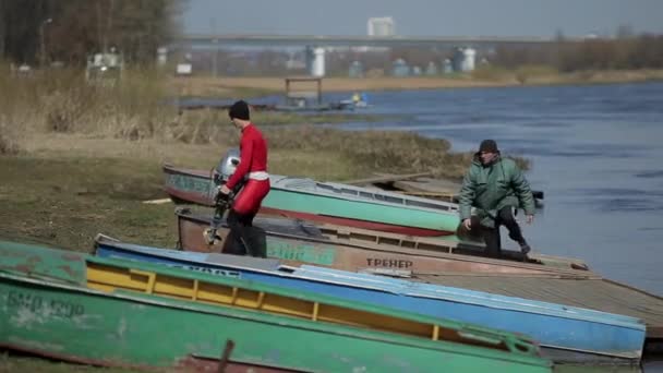 Bobruisk, Bielorrússia - 11 de maio de 2019: Um homem carregando motor de barco . — Vídeo de Stock