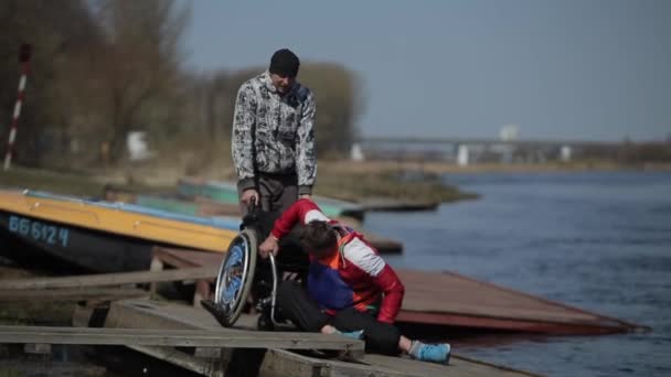 Bobruisk, Belarus - 11 May 2019: disabled athlete sits in a wheelchair after training Rowing, canoeing, paddling. Training. Kayaking. wheel chair on berth. — Stock Video