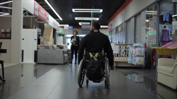 Bobruisk, Bielorrusia - 11 de mayo de 2019: personas con discapacidad viajan en silla de ruedas en el centro comercial . — Vídeos de Stock