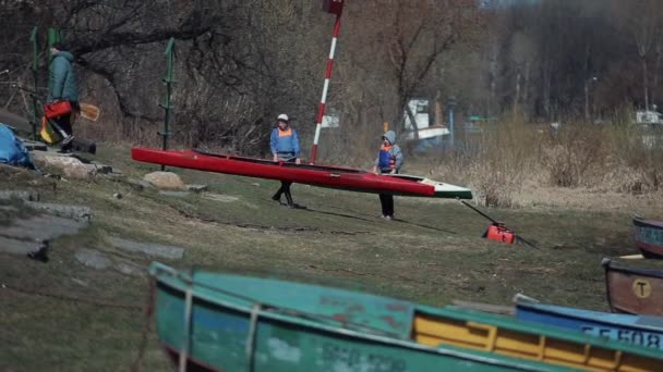 Bobruisk, Λευκορωσία-11 Μαΐου 2019: οι τύποι μεταφέρουν καγιάκ για αθλήματα. Καλοκαιρινά θαλάσσια σπορ. Κωπηλασία, κανό, κουπί. Κατάρτισης. Καγιάκ. Τα παιδιά φέρνουν τη βάρκα πίσω στη βάση — Αρχείο Βίντεο