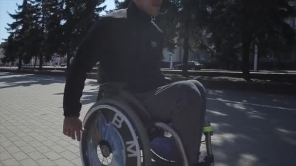 Bobruisk, Bielorrússia - 11 de maio de 2019: cadeira de rodas para deficientes no parque. Sozinho deficiente cara . — Vídeo de Stock