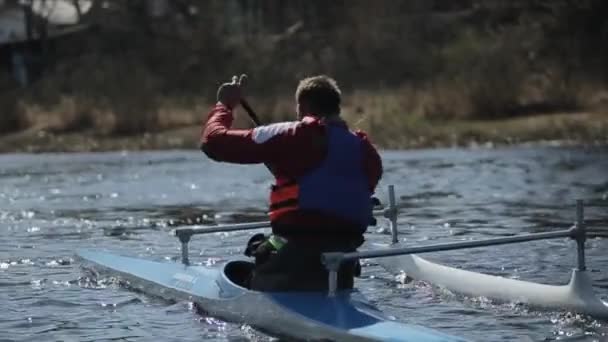 Bobruisk, Bielorrusia - 11 de mayo de 2019: Vista trasera del hombre remando en una canoa. Remo, piragüismo, remo. Entrenamiento. Kayak. Tracking Shot. Movimiento lento . — Vídeos de Stock