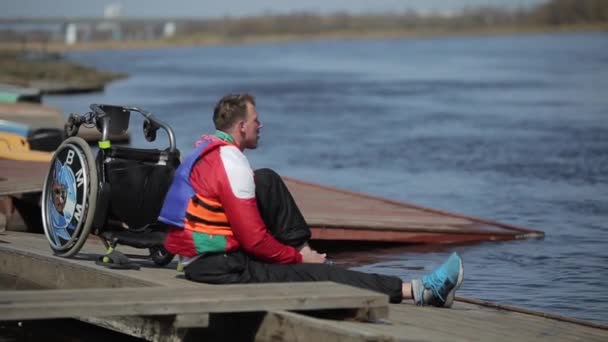 Bobruisk, Λευκορωσία-11 Μαΐου 2019: ο αθλητής είναι ανάπηρος καθισμένος στην αποβάθρα και φορώντας αθλητικά παπούτσια μετά την προπόνηση με κανό. Κωπηλασία, κανό, κουπί. Κατάρτισης. Καγιάκ. — Αρχείο Βίντεο