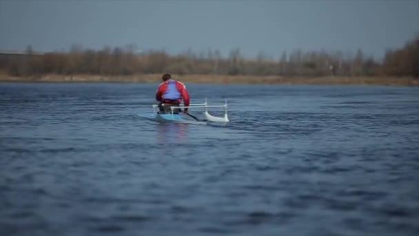 카누를 타고 강에서 노를 젓는 선수의 뒷모습. 조정, 카누, 패들링. 훈련. 카약. 다리를 건너 항해하는 남자. — 비디오