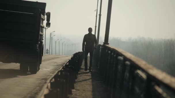 Un joven caminando por el puente. Los coches van por la carretera. Mañana y niebla. Primavera . — Vídeo de stock