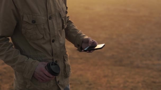 Cep telefonu kullanarak adam açık havada kapatın ve bant kaydırır. Adam kahve içiyor ve telefonda konuşuyor.. — Stok video