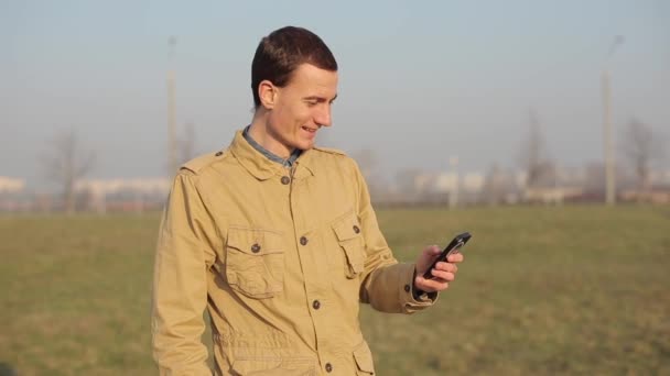 Lycklig galen rödhårig kaukasiska killen använda en smart telefon utomhus. Chatta rullning och använda Internet. kolerisk person skrattar och talar högljutt. — Stockvideo