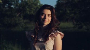 Kıvırcık siyah saçlı güzel beyaz genç kız closeup mutlu yaşam tarzı portre. Kadın gülümsüyor ve kameraya bakıyor. Arka planda yeşil bahçe. Ormanda kız