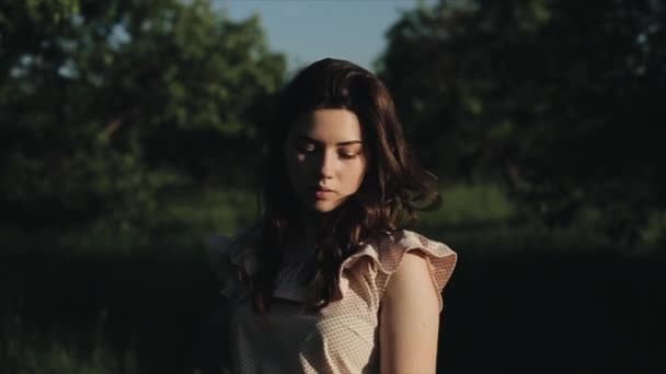 Primer plano estilo de vida feliz retrato de chica joven bastante caucásica con el pelo negro rizado. La mujer sonríe y mira a la cámara. Patio verde en el fondo. Chica en el bosque — Vídeos de Stock