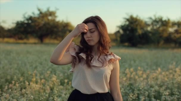 Retrato de uma linda garota andando no campo. A menina se afasta da câmera e sorri — Vídeo de Stock