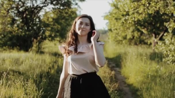 Mooi vrolijk gelukkig jong meisje dragen zwarte rok met golvende haren wandelingen in het pad in bos verstrooit haar en glimlacht en spins. — Stockvideo