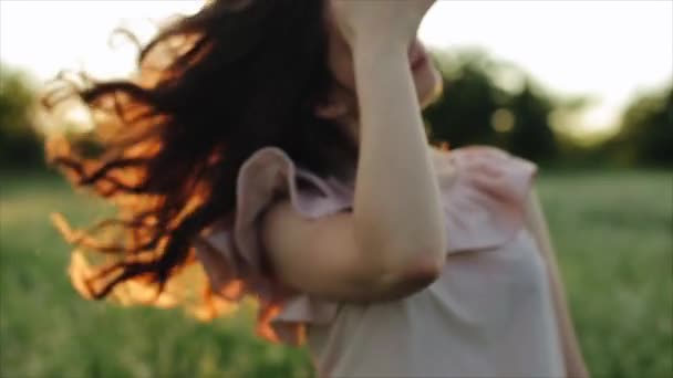 Mooi meisje neemt haar haar op zonsondergang achtergrond. — Stockvideo