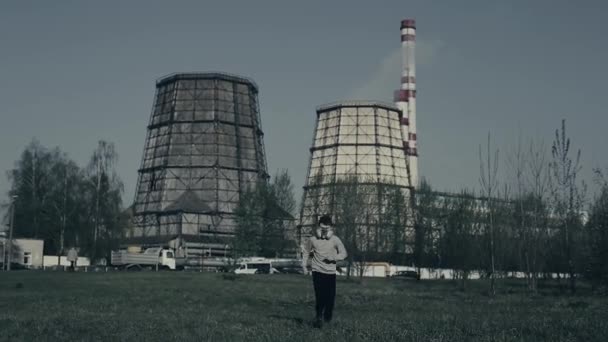 Mladý chlapec běží proti komínu z továrny. Koncepce znečištění ovzduší. Zavři portrét mladého chlápka na pozadí. Chlapec plyne ze znečištění. — Stock video