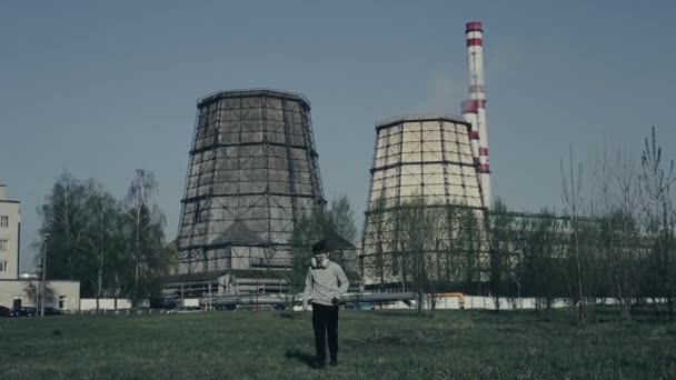 Genç çocuk fabrika bacalarına karşı koşuyor. Hava kirliliği kavramı. Arka planda genç adam witn bitki yakın portresi. Çocuk kirlilikten nefes kesti. — Stok video