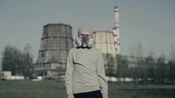 工場の煙突に対して汚染マスクを着用した少年。大気汚染の概念。グレーカップと人工呼吸器の子供. — ストック動画