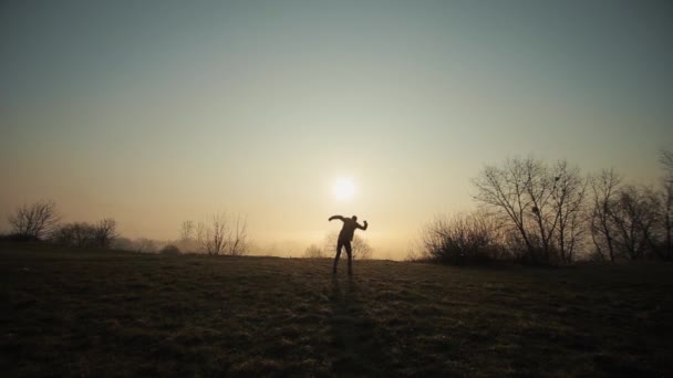 Silhouette eines lustigen Verrückten, der gegen Sonnenaufgang oder Sonnenuntergang tanzt. erfolgreicher fröhlicher und fröhlicher Mann, der auf dem Hintergrund der Sonne tanzt. — Stockvideo