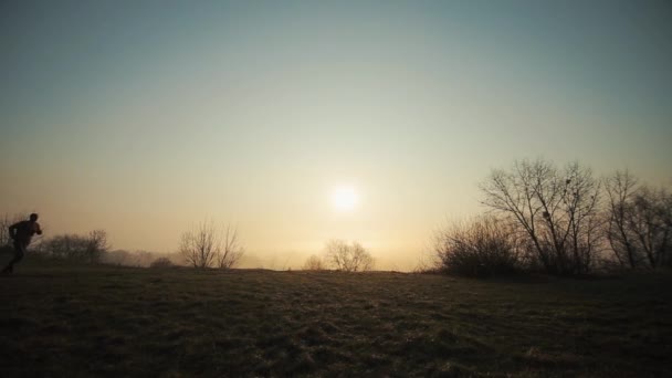 Silhouette eines Laufenden am Morgen gegen den Sonnenaufgang. — Stockvideo