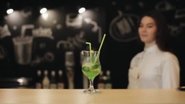 Bir bar tezgahında duran bir mojito kokteyl çalışıyor güzel bir genç kız