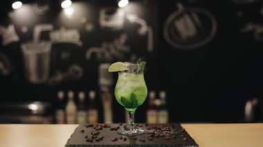 Bir bardak bakire mojito bar tezgahında izole edilmiş. Bir barmen içkinin içine yeşil bir pipet koyar.