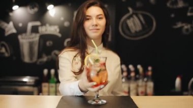 Güzel gülümseyen esmer bir bar sayacında çilek mojito birkaç yudum alır