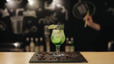 Gülümseyen bir erkek barmen bir bar sayacı üzerinde mojito bir saman koyar