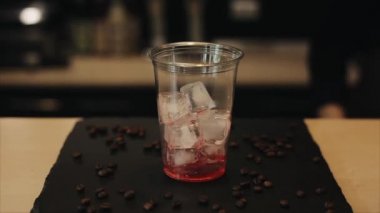 Barista el buz küpleri ile bir fincan içine çilek şurubu, limonata ve espresso dökülüyor. Close