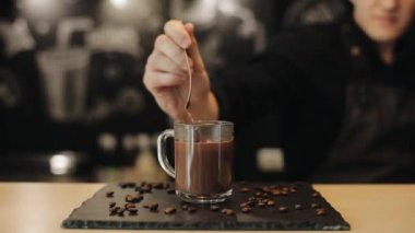 Barmen sıcak çikolata bir bardak bardak içine bir kaşık dökmek yapma. Close