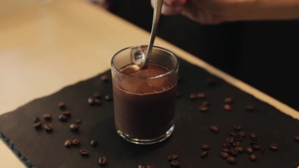 Zbliżenie gorącej czekolady, która spada z łyżki do pełnego szklanego kubka — Wideo stockowe