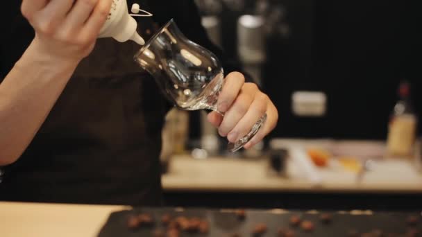 Närbild av manliga hand klämma en flaska choklad, dekorera en tom tulpan glas — Stockvideo