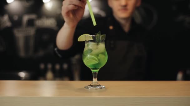 Mannelijke Barista hand putting twee groene rietjes in Mojito — Stockvideo