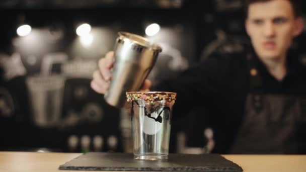 Männliche Barkeeper Hand gießt Milchshake in eine Tasse zum Mitnehmen mit etwas Schokolade und Süßwaren-Dressing darauf — Stockvideo
