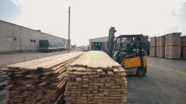 Bobruisk, Beyaz Rusya - 11 Mart 2019: Forklift operatörü depoda ahşap paletler ile ilgileniyor. Ahşap kalas yükleyici dor Paketi kullanan adam.