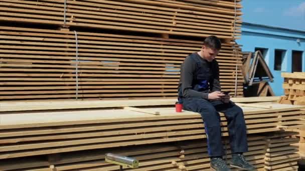 Будівельник чоловіка в уніформі сидить на довгих дошках . — стокове відео