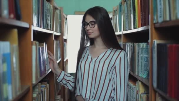 Bobruisk, Bielorussia - 15 giugno 2019: Pretty young Girl with long black hair goes between the shelf in the library . — Video Stock