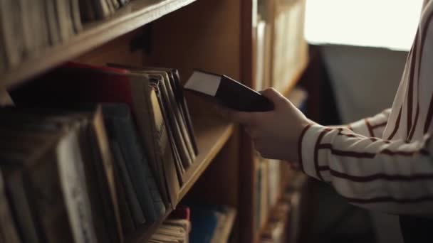 Primer plano de las manos femeninas en busca de un libro de una estantería en la biblioteca — Vídeo de stock