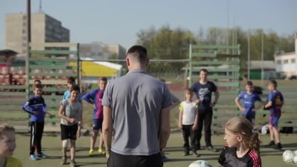 ボブリスク、ベラルーシ - 2019年6月15日:若いサッカーチームが試合前にウォーミングアップ。子供たちは運動をするサッカーコーチは子供たちを訓練します. — ストック動画