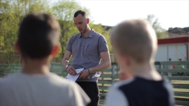 Jonge voetbalcoach trainer coaching kinderen met behulp van tactiek strategie magnetische whiteboard. Voetbaltrainer met uitleg wedstrijd tactieken voor kinderen voetbalteam. — Stockvideo